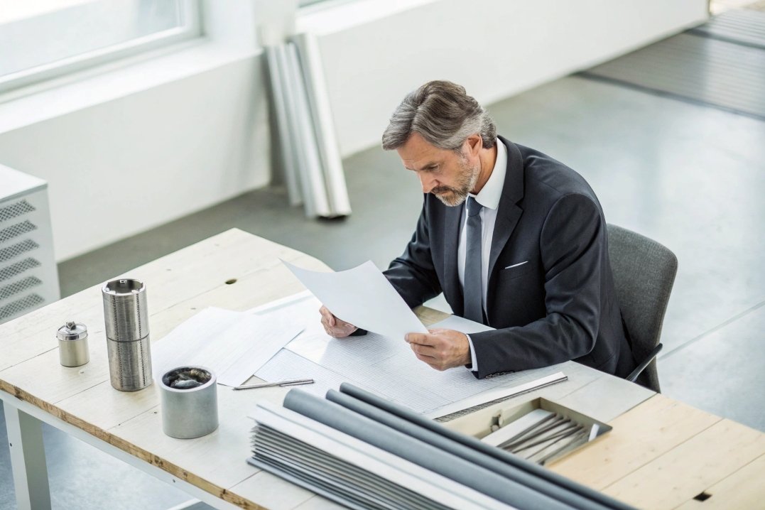 Engineer reviewing blueprints, assessing industrial materials, supply chain management