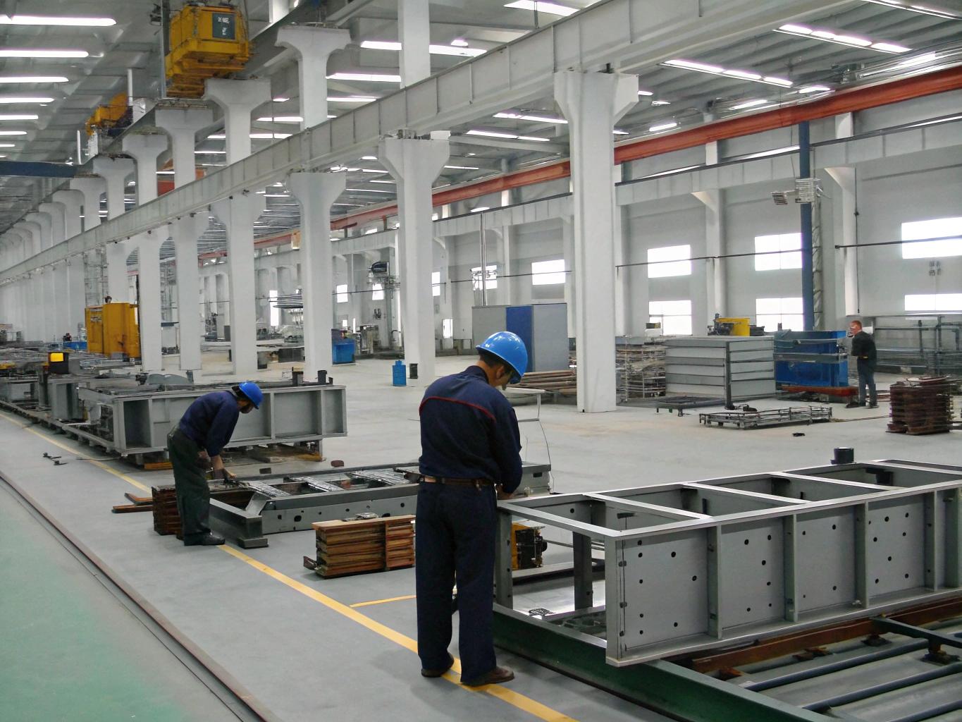 Workers assembling large steel structures in factory