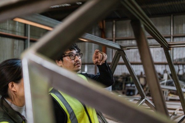 Engineer in safety vest inspecting metal frame (ID#2)