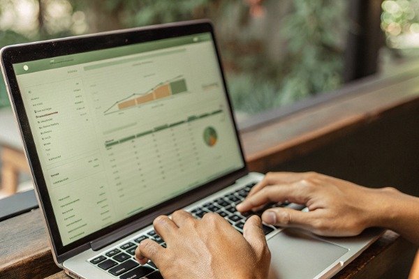 Person typing on laptop with company data verification screen (ID#4)