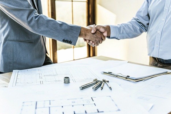 Business handshake over blueprints (ID#5)