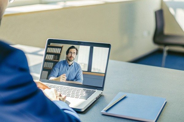 Person video conferencing on laptop at desk (ID#4)