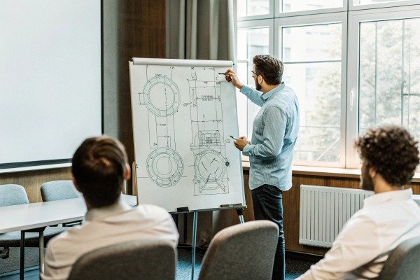 Man presenting technical drawing on whiteboard (ID#5)