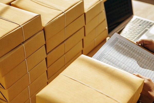 Person checking inventory list near stacked boxes (ID#3)