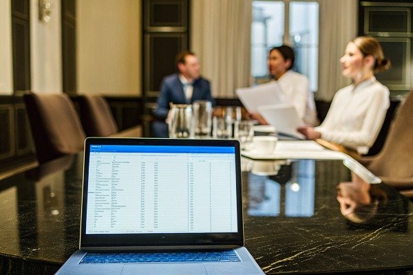 Laptop with spreadsheet in meeting room with people (ID#5)