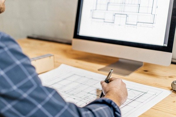 Engineer drawing architectural plans at desk (ID#2)