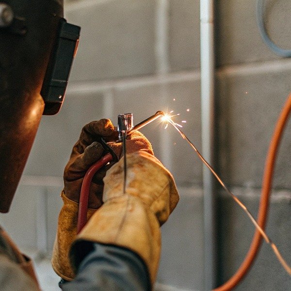 Worker welding metal with protective gloves (ID#1)