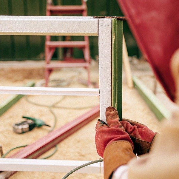 Worker assembling metal frame with gloves (ID#1)
