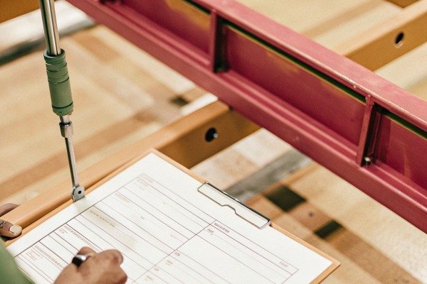 Person filling out form on clipboard near machinery (ID#5)