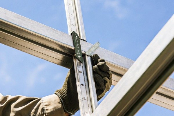 Gloved hand adjusting metal frame with blue sky (ID#4)