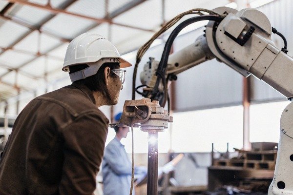 Worker operating robotic arm in industrial setting (ID#3)