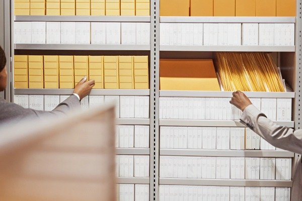 Hands organizing yellow and white files on shelves (ID#4)