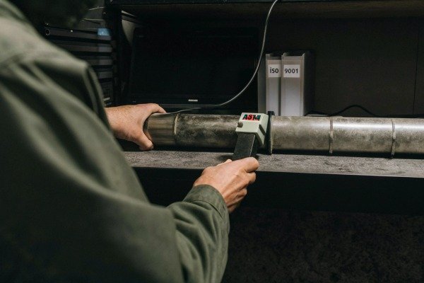 Technician testing metal pipe with device (ID#2)