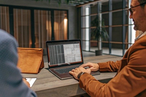 Man working on laptop with architectural plans (ID#5)