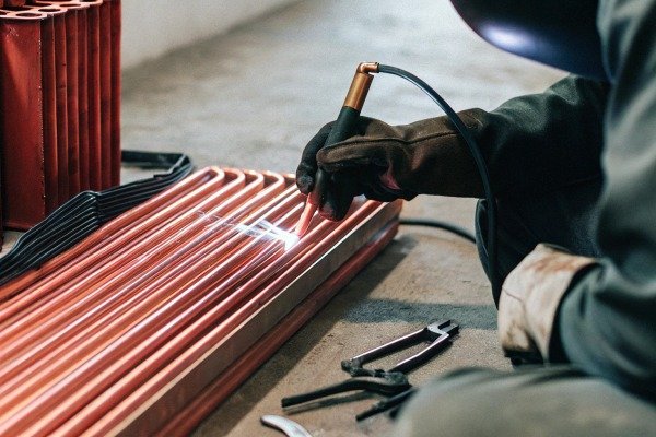 Worker welding copper pipes with protective gloves (ID#4)