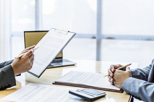 Business meeting reviewing documents with calculator (ID#2)