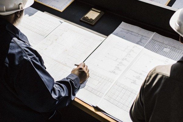 Engineers reviewing technical drawings at desk (ID#2)