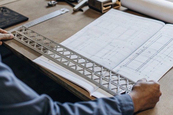 Person using metal ruler on engineering blueprint (ID#4)