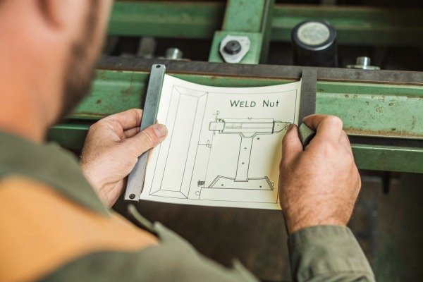 Man holding weld nut blueprint drawing (ID#5)
