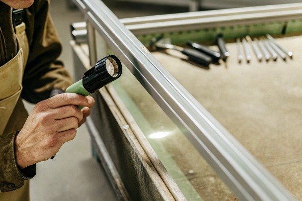 Person inspecting metal frame with flashlight (ID#3)