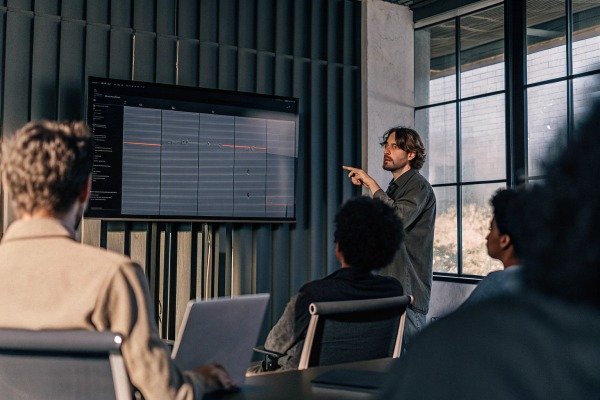 Man presenting data on screen to team meeting (ID#5)