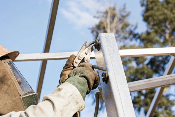 Welder using tool on metal structure outdoors (ID#4)