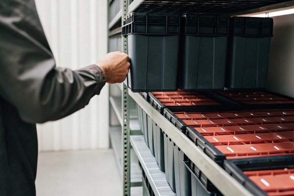 Worker organizing plastic bins on metal shelves (ID#4)