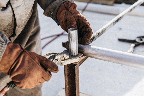 Worker welding metal pipe with gloves (ID#3)