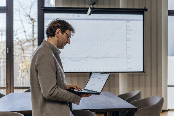 Man analyzing data on laptop in office (ID#3)