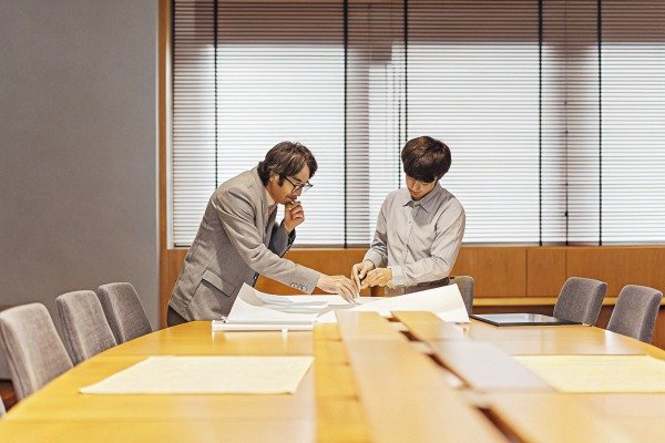 Two men reviewing blueprints in meeting room (ID#4)