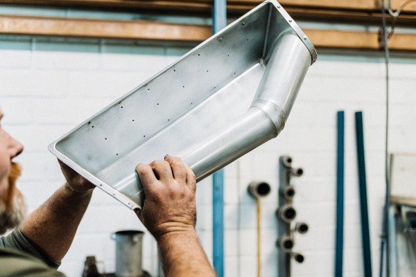 Worker inspecting metal duct in factory (ID#3)