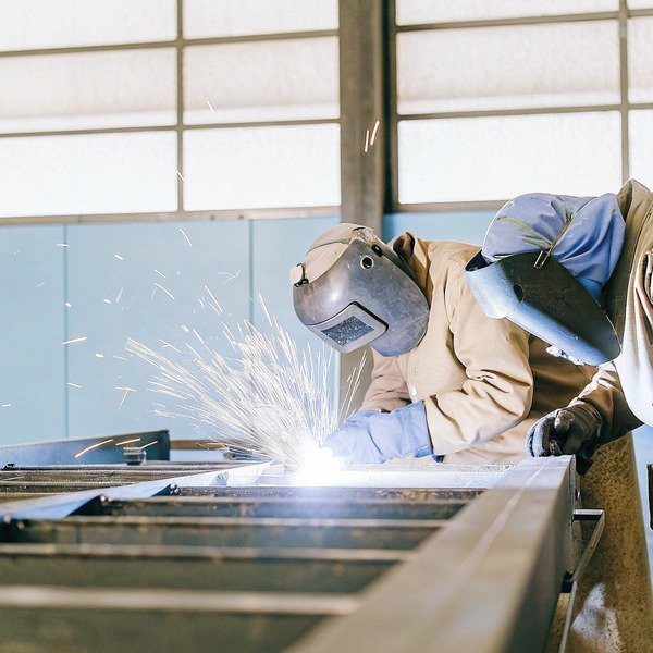 Welder working with sparks in industrial workshop (ID#1)