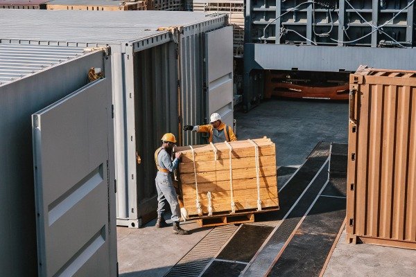 Workers loading wooden crate into shipping container (ID#5)