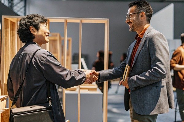 Two men shaking hands at business event (ID#5)