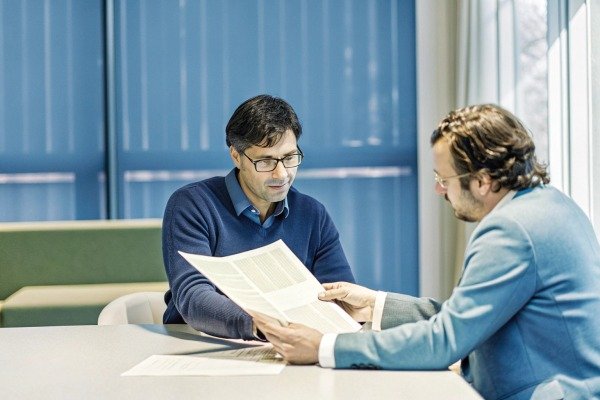 Two men discussing documents in office (ID#5)