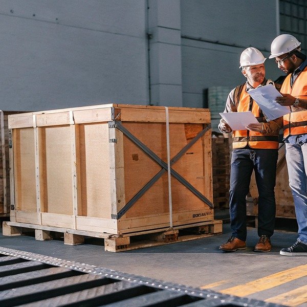 Workers inspecting large wooden crate in warehouse (ID#1)