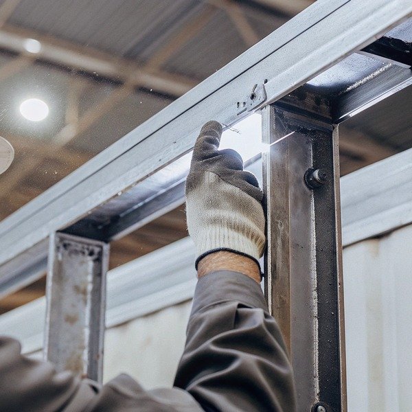 Worker inspecting metal frame in factory (ID#1)