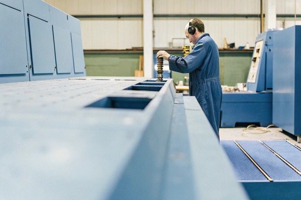 Technician operating large blue industrial machine (ID#3)