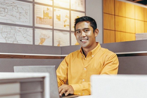 Smiling man in yellow shirt at office desk (ID#4)