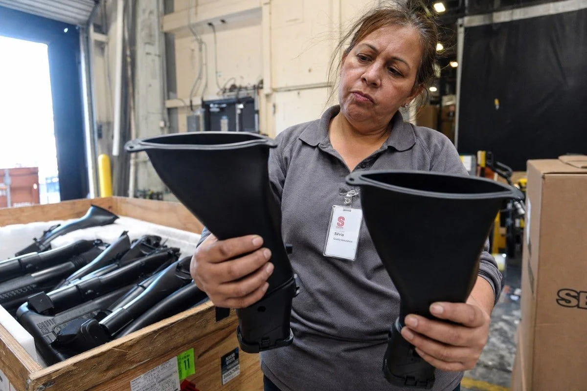 Worker holding automotive duct part to check for warping and design balance (ID#3)